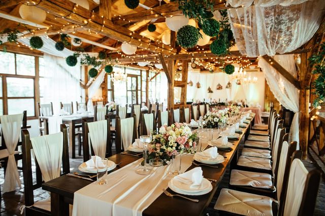 A rustic barn wedding reception set with long tables and hanging lights