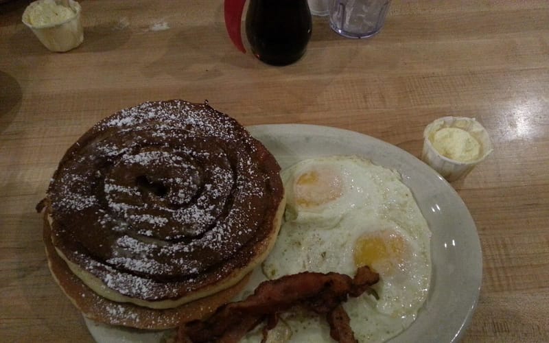 A diner breakfast plate of pancakes, bacon, and eggs