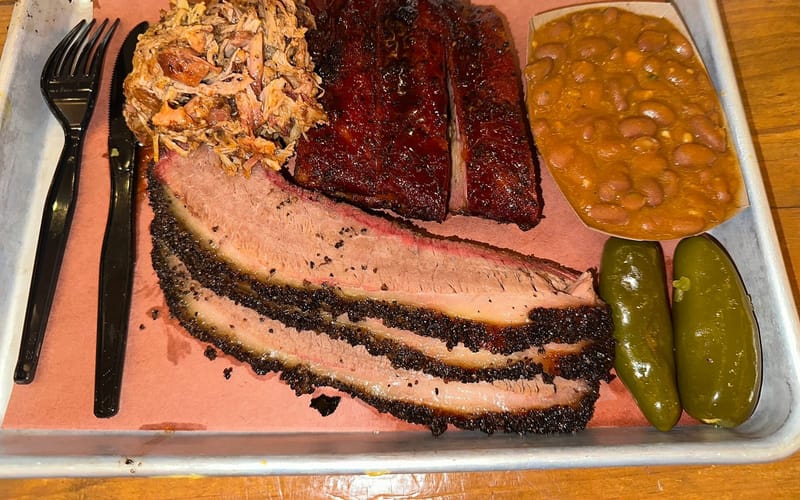 A plate of brisket, barbecue ribs, pulled pork, and beans