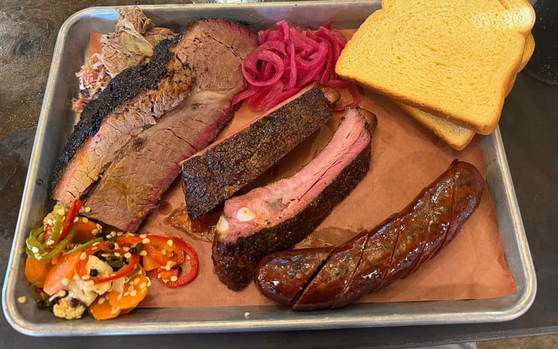 A barbecue tray of brisket, pork ribs, sausage, and pulled pork