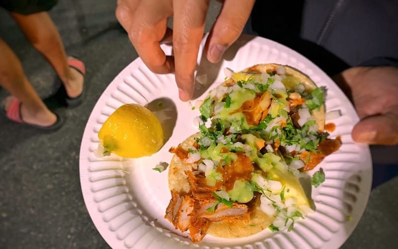 Tacos al pastor topped with onions, cilantro, and pineapple