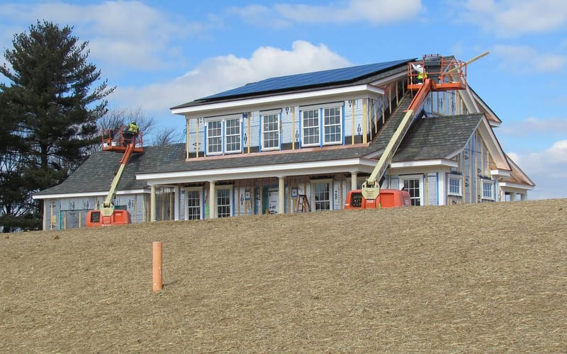 A crew installing asphalt shingles on a roof
