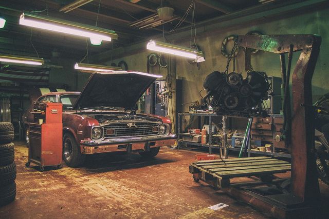 The interior of a car repair shop with an engine on a hoist
