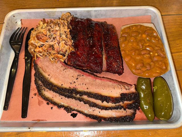 A plate of brisket, barbecue ribs, pulled pork, and beans