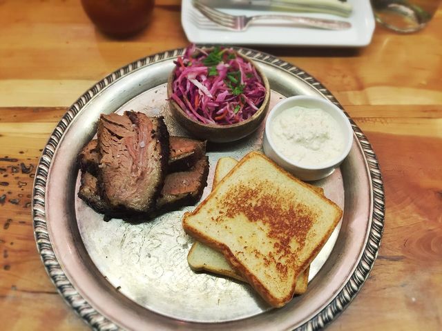 Sliced smoked brisket with white bread, horseradish, and slaw