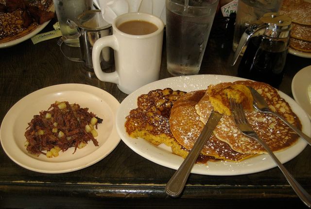 A breakfast plate of pancakes with a side of hash