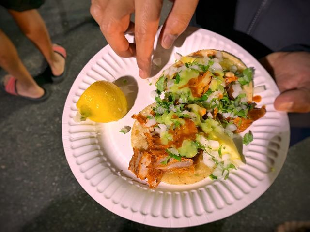 Tacos al pastor topped with onions, cilantro, and pineapple