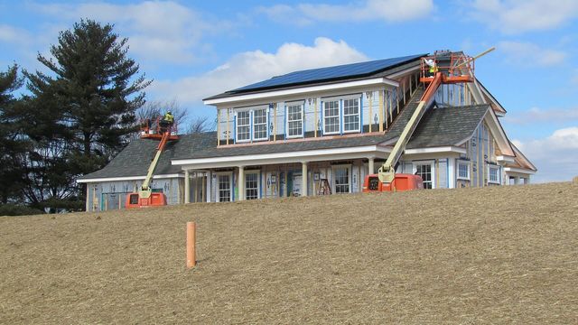 A crew installing asphalt shingles on a roof